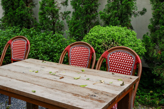 Luxury chair and wooden table set in english garden on a sunny day,outdoor seating for restaurant or cafe,Near paver patio with sitting area and small garden in forest.
