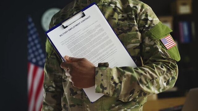 African American U.S. serviceman holds military employment contract in office