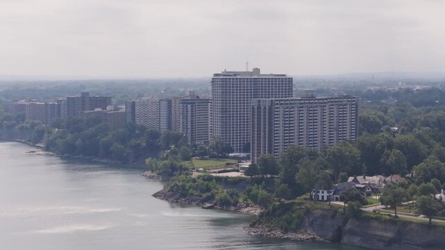 Drone aerial of condominium complex residential building and buildings along shoreline and Lake Erie coast outside Cleveland, OH by waterscape and waterfront of Ohio northern shore apartment structure