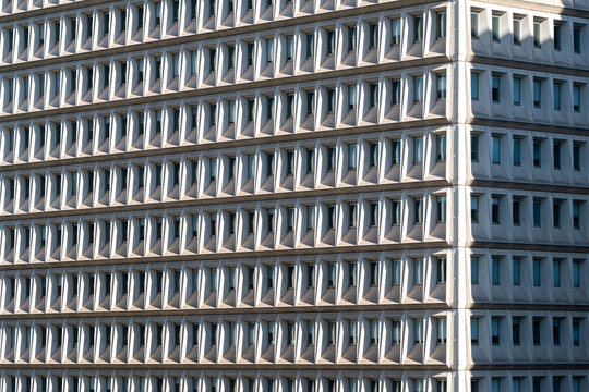 A facade turns at the corner as frames organize windows into a precise grid, where repetition and symmetry turn modern architecture into a graphic pattern.