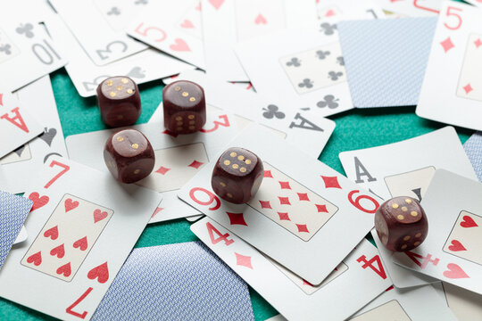 Playing cards and wooden dice on a green cloth.