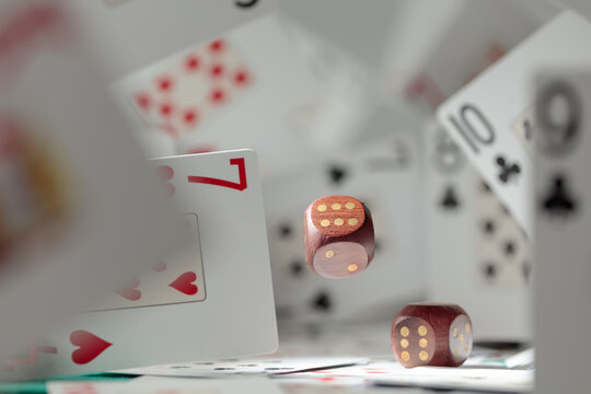 Wooden die in motion surrounded by playing cards.