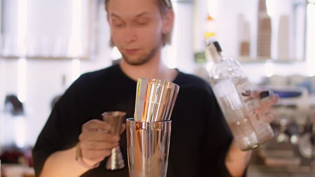 Bar drink recipe. Barkeeper counter. Man professionally adding alcohol color flavored syrup with jigger to shaker preparing cocktail.