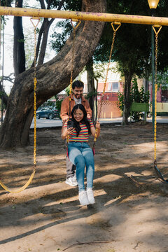 Young couple having fun on swings in a park.