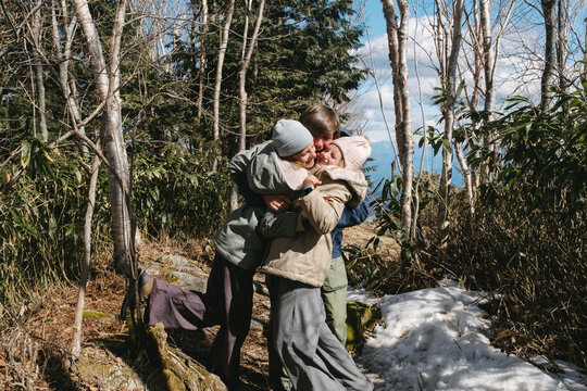 Happy family hugging in snowy forest.