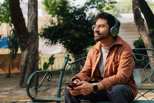 Young man enjoying music with headphones in an urban park