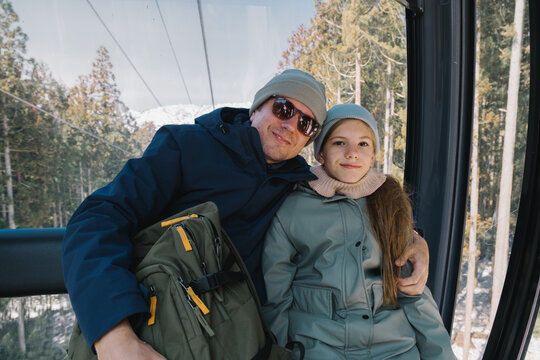 Smiling father and daughter in a cable car.