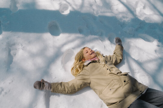Happy girl making snow angel.