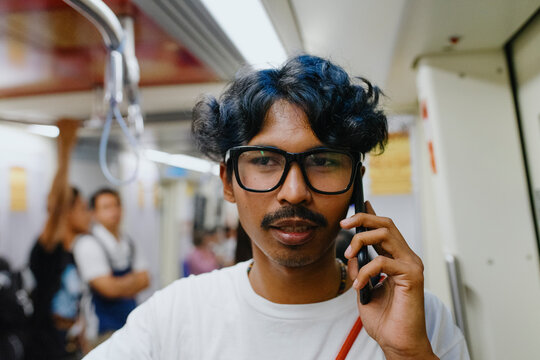 Young Man Talking on Phone while riding skytrain