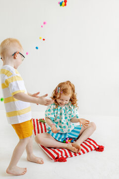 Kids play with colorful pom poms on a mat