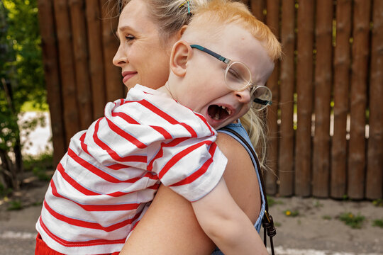 A mother holds a child in her arms in a park.