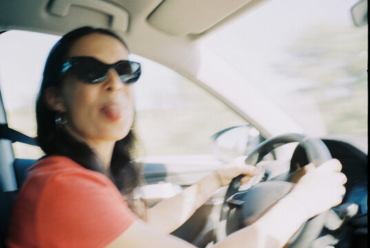 Woman Driving with Playful Expression in Car. Blurred