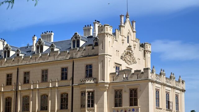 The facade of Lednice Castle with battlements, tall chimneys and a carved coat of arms, Czech Republic