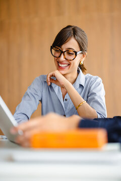 Woman Smiles While Working on a Laptop in a Modern Office Space