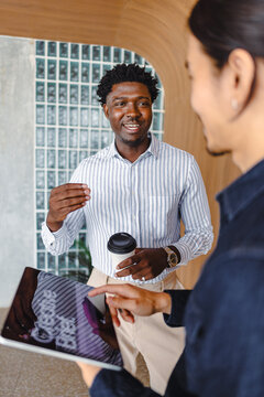 Two People Talking in Office Space With Tablets and Coffee
