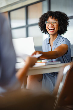 Woman Smiles While Working at a Table With a Laptop in a Bright Space
