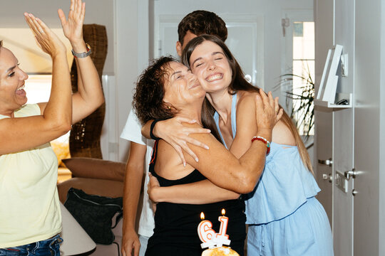 Family celebrating mother's 61st birthday giving a hug
