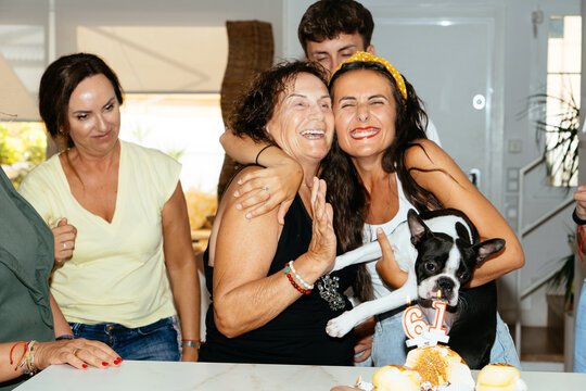 Family celebrating birthday with cake and boston terrier dog
