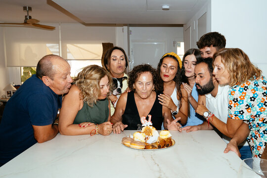 Extended family celebrating birthday party blowing candles