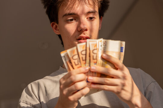 Teenager reacting with shock to fanned euro banknotes