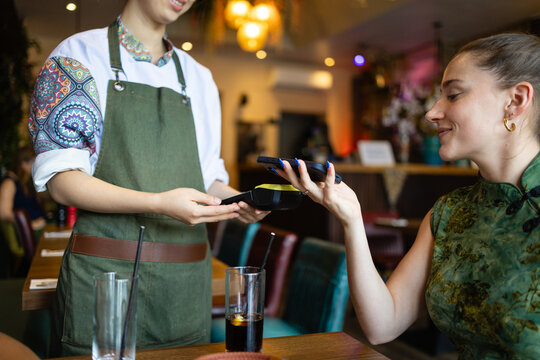 Woman paying with contactless card at restaurant