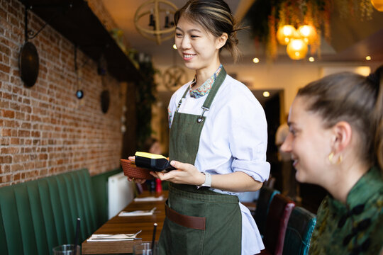Smiling waitress holding card reader for customer