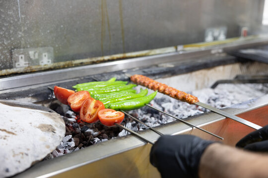 Grilling Turkish kebab skewers and vegetables over hot charcoal