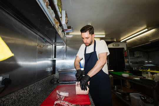 Focused chef cutting raw lamb meat
