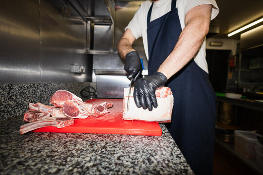 Close-up of a chef cutting raw lamb chops 