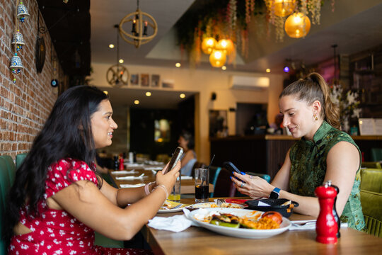Friends checking smartphones during restaurant meal