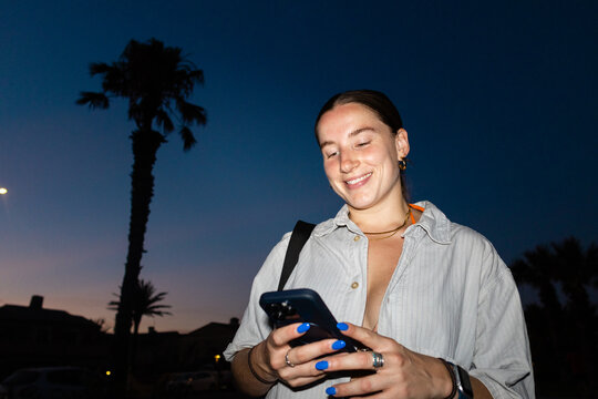 Woman smiling at phone during evening in Benic&agrave;ssim