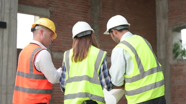 Architects and construction engineers review structural and architectural plans at a building site. Concept of construction planning, structural design, teamwork, and project development.