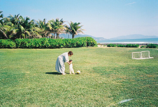 Mother and child playing with a soccer ball on a grassy field