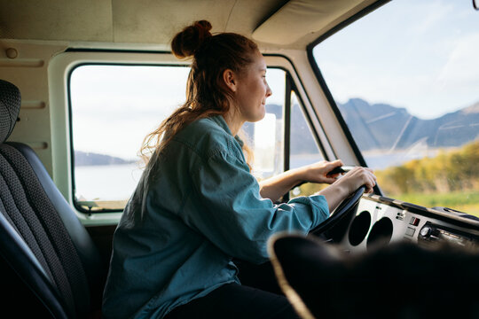 Woman driving camper van feeling freedom on road trip