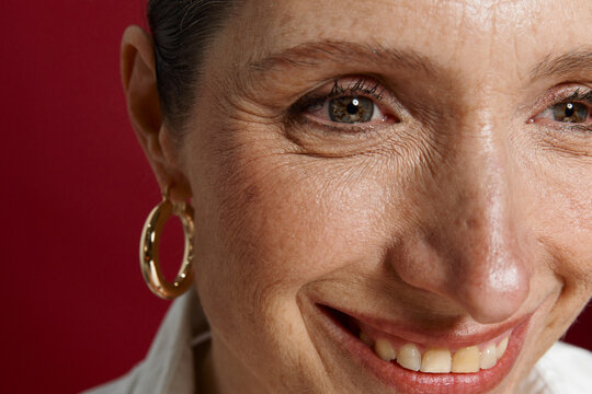 Woman Smiling Against a Bright Red Background in a Close-Up Shot