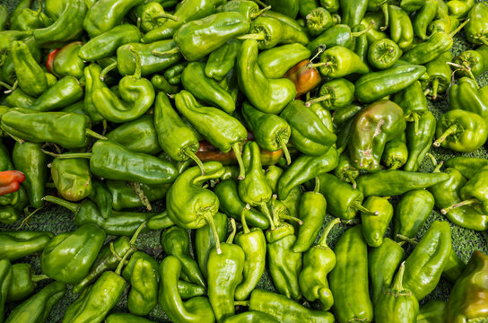 Vibrant green Italian frying peppers are stacked at a fresh vegetable market in Italy during the day