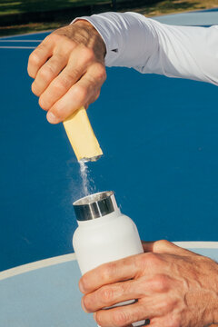 Pouring electrolyte powder supplement into water bottle