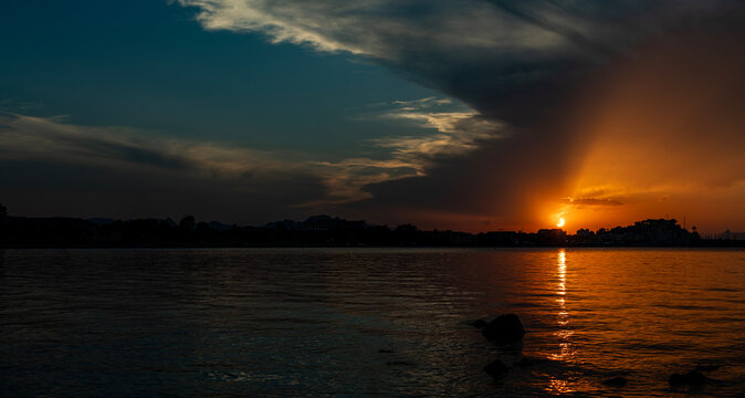 Panoramic sunset view of the solar eclipse over the sea and D&eacute;nia coastline with dark clouds and golden light