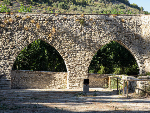 Two stone arches of ancient aqueduct surrounded by trees in a natural setting
