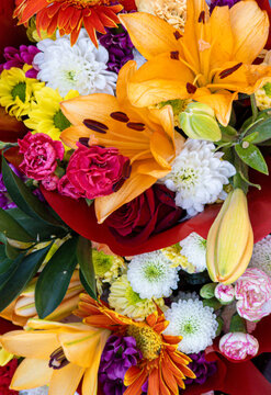 Bright bouquet with orange lilies, red carnations, roses, and white chrysanthemums arranged in a colorful display