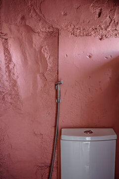 Bathroom With Pink Wall and White Toilet in a Simple Setting