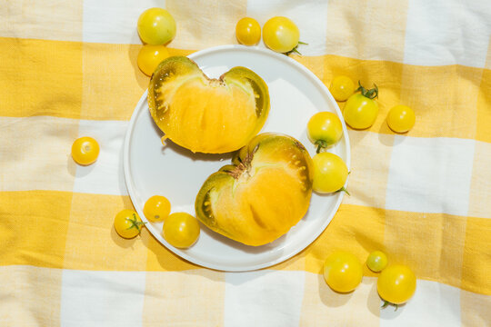 Sliced heirloom tomato on plate with yellow cherry tomatoes