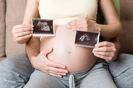 Portrait of young happy married couple hold ultrasound picture. Diverse man and pregnant woman show sonogram image on kid child, excited for parenthood. Parenting concept