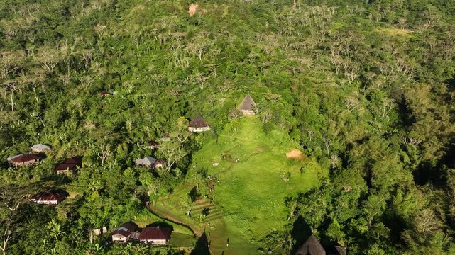 Aerial view of the traditional conical houses of Waerebo Village nestled in a lush green forest clearing in Satar Mese Barat, East Nusa Tenggara, Indonesia.