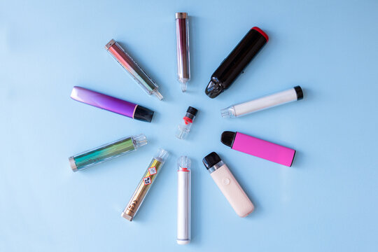 Various electronic smoke devices clustered together, some showing danger symbols. Represents the risks of addiction and health issues.