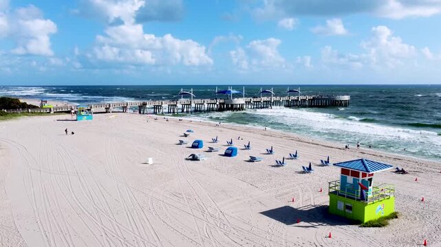 Aerial view drone video of Beach guard house Pompano Beach and Pier in background, blue ocean and sea waves FL USA Miami beach, sunny day, sky blue EEUU 4k
