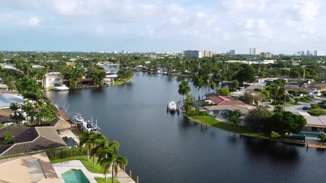 Aerial view drone video of a residential neighborhood, houses near lake with pools, cars, boats, bridges, tropical plants, palm trees, Pompano Beach Fl USA Miami beach, sunny day