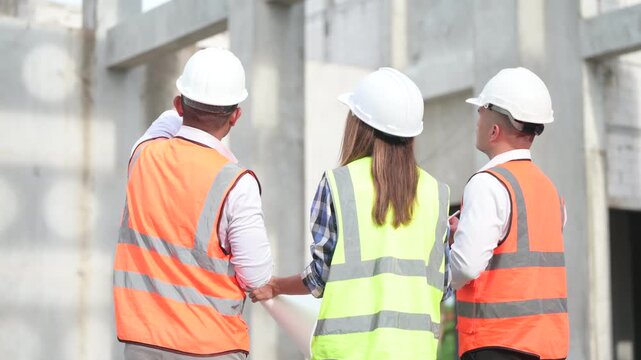 Architects and construction engineers review structural and architectural plans at a building site. Concept of construction planning, structural design, teamwork, and project development.