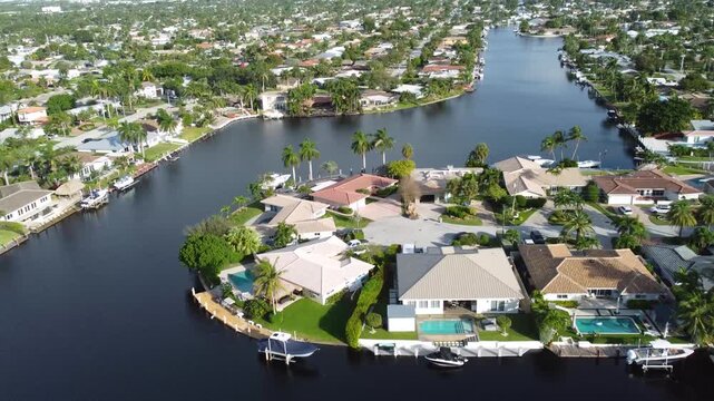Aerial view drone video of a residential neighborhood, houses near lake with pools, cars, boats, bridges, tropical plants, palm trees, Pompano Beach Fl USA Miami beach, sunny day.