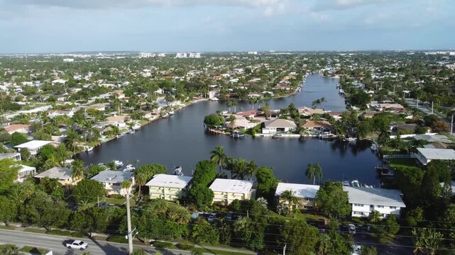 Aerial view drone video of a residential neighborhood, houses near lake with pools, cars, boats, bridges, tropical plants, palm trees, Pompano Beach Fl USA Miami beach, sunny day.